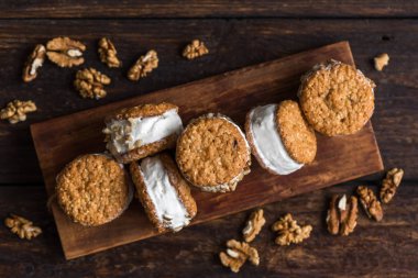 Dondurma sandviç ile fındık ve kepekli kurabiye. Ev yapımı vanilyalı dondurma sandviç koyu ahşap arka plan üzerinde.