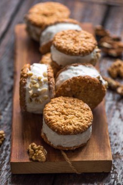 Dondurma sandviç ile fındık ve kepekli kurabiye. Ev yapımı vanilyalı dondurma sandviç koyu ahşap arka plan üzerinde.