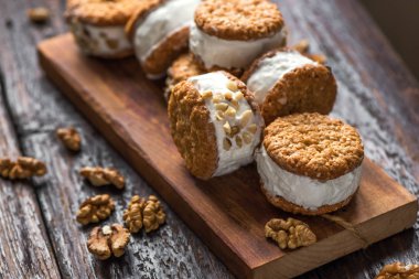 Dondurma sandviç ile fındık ve kepekli kurabiye. Ev yapımı vanilyalı dondurma sandviç koyu ahşap arka plan üzerinde.