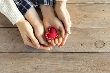 Kırmızı kalp ahşap arka plan, kopya alanı üzerinde çocuk ve kadın elinde. İyilik, Aile, sevgi ve hayır kurumu genel kavram, el yapımı sevgililer ya da anneler günü hediyesi.