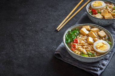 Japon ramen çorba tofu ve karanlık taş zemin üzerine yumurta ile. Ramen noodle ve tofu seramik kase, Asya geleneksel yemekleri ile miso çorbası.