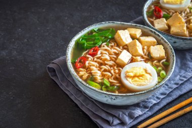Japon ramen çorba tofu ve karanlık taş zemin üzerine yumurta ile. Ramen noodle ve tofu seramik kase, Asya geleneksel yemekleri ile miso çorbası.