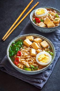 Japon ramen çorba tofu ve karanlık taş zemin üzerine yumurta ile. Ramen noodle ve tofu seramik kase, Asya geleneksel yemekleri ile miso çorbası.