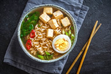 Japon ramen çorba tofu ve karanlık taş zemin üzerine yumurta ile. Ramen noodle ve tofu seramik kase, Asya geleneksel yemekleri ile miso çorbası.