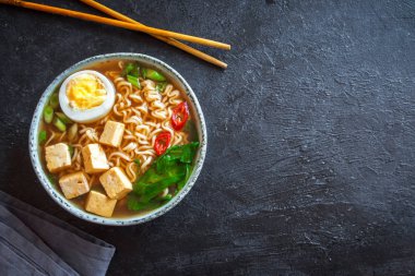 Japon ramen çorba tofu ve karanlık taş zemin üzerine yumurta ile. Ramen noodle ve tofu seramik kase, Asya geleneksel yemekleri ile miso çorbası.