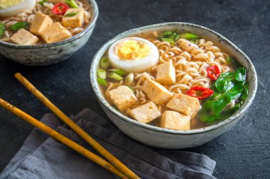 Japon ramen çorba tofu ve karanlık taş zemin üzerine yumurta ile. Ramen noodle ve tofu seramik kase, Asya geleneksel yemekleri ile miso çorbası.