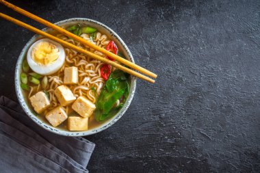 Japon ramen çorba tofu ve karanlık taş zemin üzerine yumurta ile. Ramen noodle ve tofu seramik kase, Asya geleneksel yemekleri ile miso çorbası.