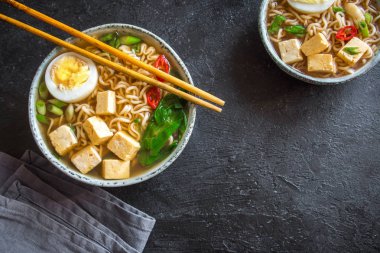 Japon ramen çorba tofu ve karanlık taş zemin üzerine yumurta ile. Ramen noodle ve tofu seramik kase, Asya geleneksel yemekleri ile miso çorbası.