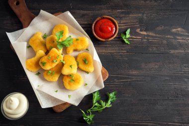 Tavuk nuggets ve koyu ahşap zemin, kopya alanı üzerine sos. Fried nuggets ketçap ve mayonez ile.