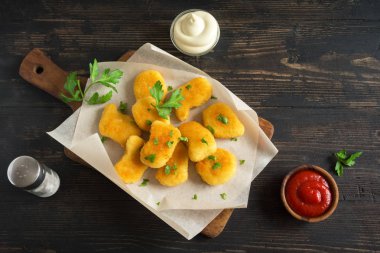 Tavuk nuggets ve koyu ahşap zemin, kopya alanı üzerine sos. Fried nuggets ketçap ve mayonez ile.