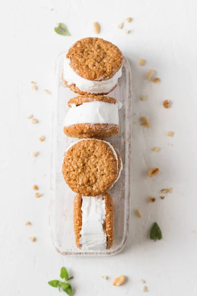 Ice cream sandwiches with nuts and wholegrain cookies. Homemade vanilla ice cream sandwiches on white background.