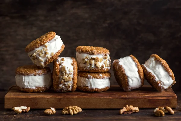 Dondurma sandviç ile fındık ve kepekli kurabiye. Ev yapımı vanilyalı dondurma sandviç koyu ahşap arka plan üzerinde.