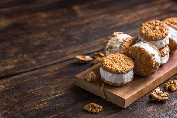 Dondurma sandviç ile fındık ve kepekli kurabiye. Ev yapımı vanilyalı dondurma sandviç koyu ahşap arka plan üzerinde.