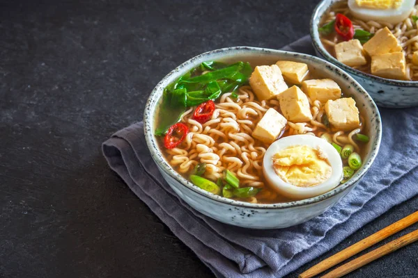 Japon ramen çorba tofu ve karanlık taş zemin üzerine yumurta ile. Ramen noodle ve tofu seramik kase, Asya geleneksel yemekleri ile miso çorbası.