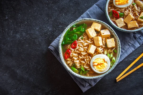 Japon ramen çorba tofu ve karanlık taş zemin üzerine yumurta ile. Ramen noodle ve tofu seramik kase, Asya geleneksel yemekleri ile miso çorbası.