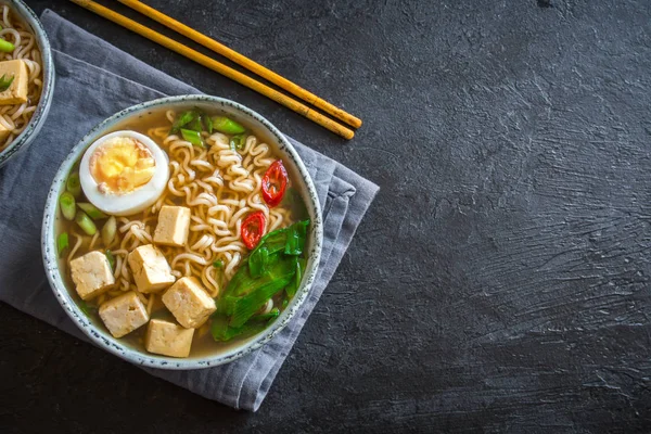 Japon ramen çorba tofu ve karanlık taş zemin üzerine yumurta ile. Ramen noodle ve tofu seramik kase, Asya geleneksel yemekleri ile miso çorbası.
