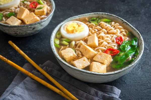 Japon ramen çorba tofu ve karanlık taş zemin üzerine yumurta ile. Ramen noodle ve tofu seramik kase, Asya geleneksel yemekleri ile miso çorbası.