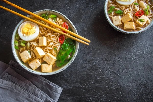 Japon ramen çorba tofu ve karanlık taş zemin üzerine yumurta ile. Ramen noodle ve tofu seramik kase, Asya geleneksel yemekleri ile miso çorbası.