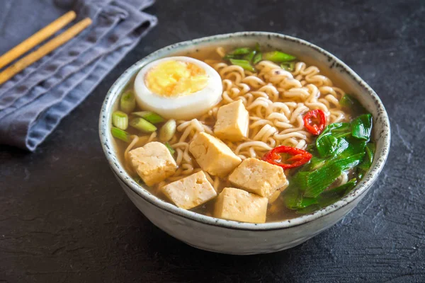 Japon ramen çorba tofu ve karanlık taş zemin üzerine yumurta ile. Ramen noodle ve tofu seramik kase, Asya geleneksel yemekleri ile miso çorbası.