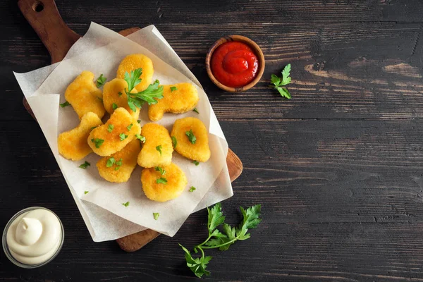Tavuk nuggets ve koyu ahşap zemin, kopya alanı üzerine sos. Fried nuggets ketçap ve mayonez ile.