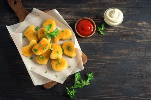 Tavuk nuggets ve koyu ahşap zemin, kopya alanı üzerine sos. Fried nuggets ketçap ve mayonez ile.