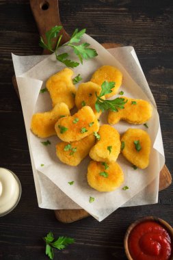 Tavuk nuggets ve koyu ahşap zemin, kopya alanı üzerine sos. Fried nuggets ketçap ve mayonez ile.