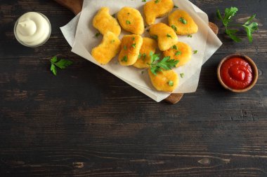 Tavuk nuggets ve koyu ahşap zemin, kopya alanı üzerine sos. Fried nuggets ketçap ve mayonez ile.