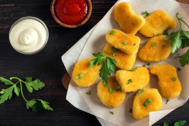 Tavuk nuggets ve koyu ahşap zemin, kopya alanı üzerine sos. Fried nuggets ketçap ve mayonez ile.