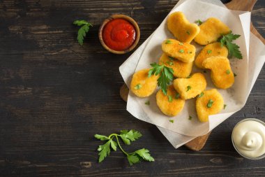 Tavuk nuggets ve koyu ahşap zemin, kopya alanı üzerine sos. Fried nuggets ketçap ve mayonez ile.