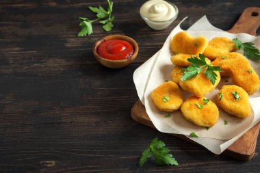 Tavuk nuggets ve koyu ahşap zemin, kopya alanı üzerine sos. Fried nuggets ketçap ve mayonez ile.