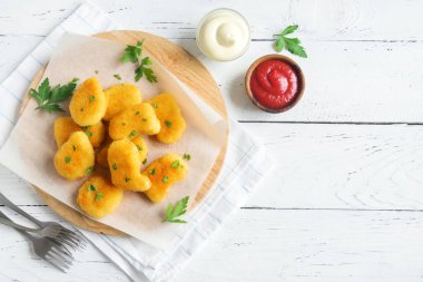 Tavuk nuggets ve beyaz ahşap zemin, kopya alanı üzerine sos. Fried nuggets ketçap ve mayonez ile.
