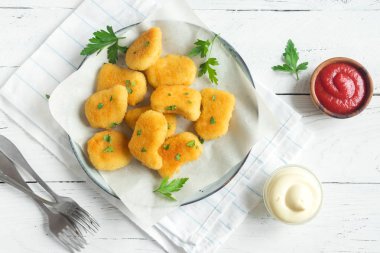 Tavuk nuggets ve beyaz ahşap zemin, kopya alanı üzerine sos. Fried nuggets ketçap ve mayonez ile.