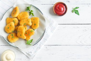 Tavuk nuggets ve beyaz ahşap zemin, kopya alanı üzerine sos. Fried nuggets ketçap ve mayonez ile.