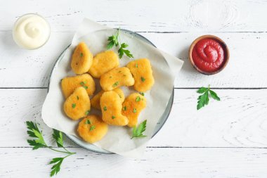 Tavuk nuggets ve beyaz ahşap zemin, kopya alanı üzerine sos. Fried nuggets ketçap ve mayonez ile.
