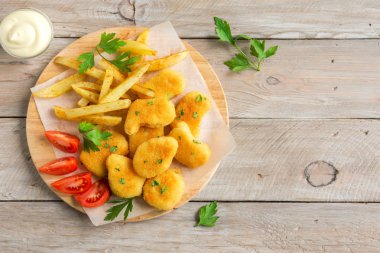 Tavuk nuggets, patates kızartması ve ahşap zemin, üzerine sosu alanı kopyalayın. Fried nuggets ve ketçap ve mayonez ile patates.