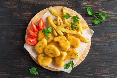 Tavuk nuggets, patates kızartması ve koyu ahşap arka plan, sosu alanı kopyalayın. Fried nuggets ve ketçap ve mayonez ile patates.