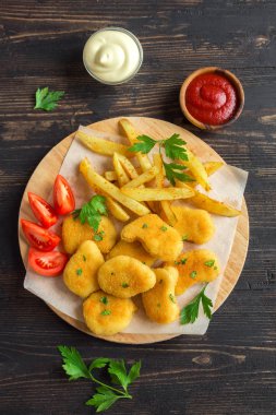 Tavuk nuggets, patates kızartması ve koyu ahşap arka plan, sosu alanı kopyalayın. Fried nuggets ve ketçap ve mayonez ile patates.