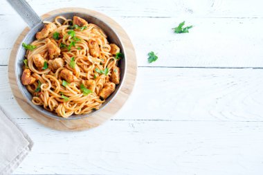 Domates soslu tavuk, maydanoz tavada spagetti makarna. Tavuk spagetti makarna kopya alanı, Italyan Mutfagi ile beyaz ahşap zemin üzerinde.