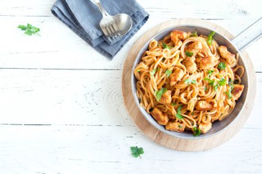 Domates soslu tavuk, maydanoz tavada spagetti makarna. Tavuk spagetti makarna kopya alanı, Italyan Mutfagi ile beyaz ahşap zemin üzerinde.
