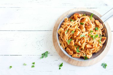 Domates soslu tavuk, maydanoz tavada spagetti makarna. Tavuk spagetti makarna kopya alanı, Italyan Mutfagi ile beyaz ahşap zemin üzerinde.