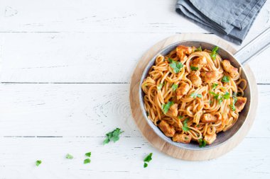 Domates soslu tavuk, maydanoz tavada spagetti makarna. Tavuk spagetti makarna kopya alanı, Italyan Mutfagi ile beyaz ahşap zemin üzerinde.