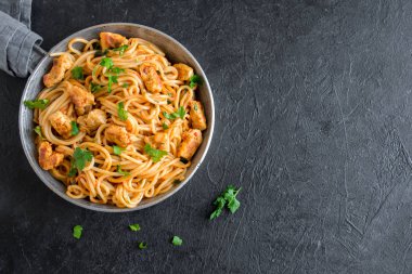 Domates soslu tavuk, maydanoz tavada spagetti makarna. Tavuk spagetti makarna kopya alanı, İtalyan yemeği siyah taş zemin üzerine.