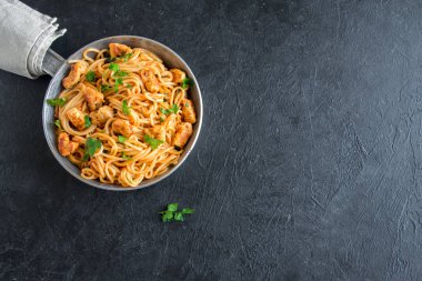 Domates soslu tavuk, maydanoz tavada spagetti makarna. Tavuk spagetti makarna kopya alanı, İtalyan yemeği siyah taş zemin üzerine.
