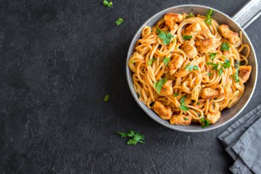Domates soslu tavuk, maydanoz tavada spagetti makarna. Tavuk spagetti makarna kopya alanı, İtalyan yemeği siyah taş zemin üzerine.