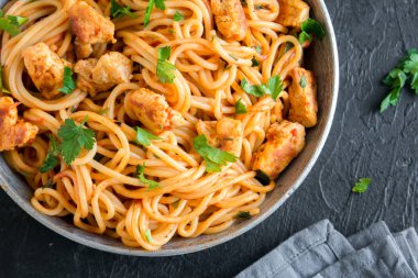 Domates soslu tavuk, maydanoz tavada spagetti makarna. Tavuk spagetti makarna kopya alanı, İtalyan yemeği siyah taş zemin üzerine.