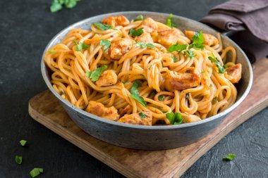 Domates soslu tavuk, maydanoz tavada spagetti makarna. Tavuk spagetti makarna kopya alanı, İtalyan yemeği siyah taş zemin üzerine.