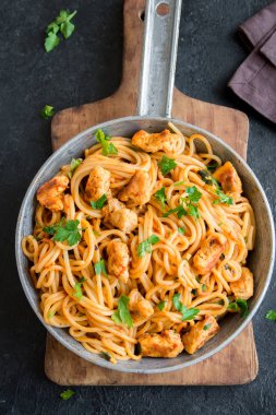Domates soslu tavuk, maydanoz tavada spagetti makarna. Tavuk spagetti makarna kopya alanı, İtalyan yemeği siyah taş zemin üzerine.