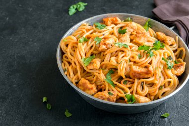 Domates soslu tavuk, maydanoz tavada spagetti makarna. Tavuk spagetti makarna kopya alanı, İtalyan yemeği siyah taş zemin üzerine.