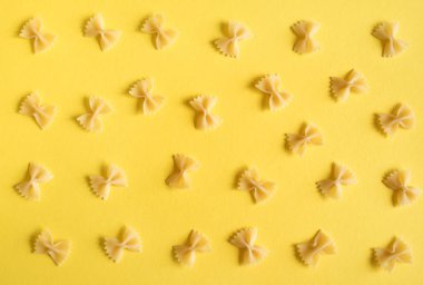 Farfalle makarna üzerine sarı arka plan, en iyi görünüm, düz yatıyordu.