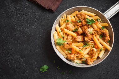 Domates soslu tavuk, maydanoz tavada penne makarna. Tavuk İtalyan penne makarna kopya alanı, Italyan Mutfagi ile siyah arka plan üzerinde.